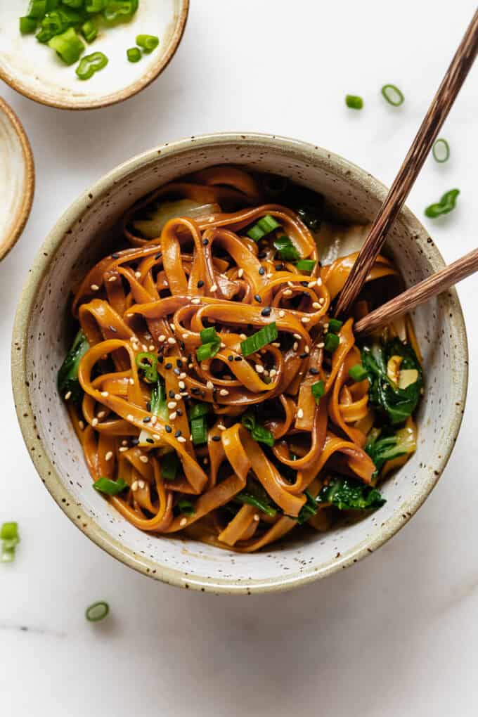 miso noodles in a white speckled bowl with wood chopsticks