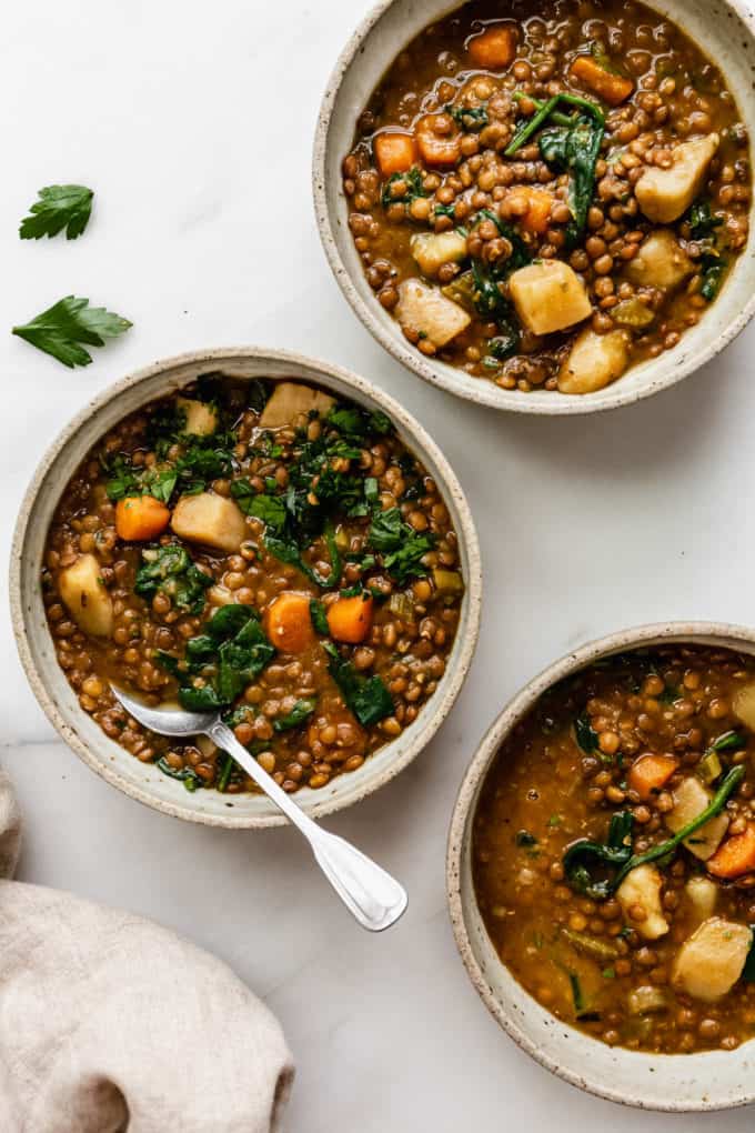 three bowls of lentil stew with parsley on top