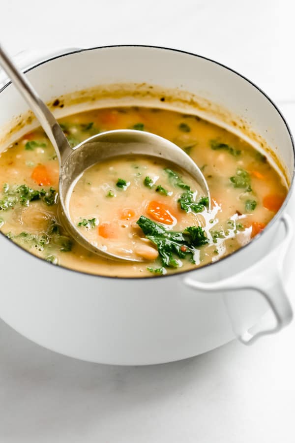 A ladel scooping out a spoon of Tuscan white bean soup