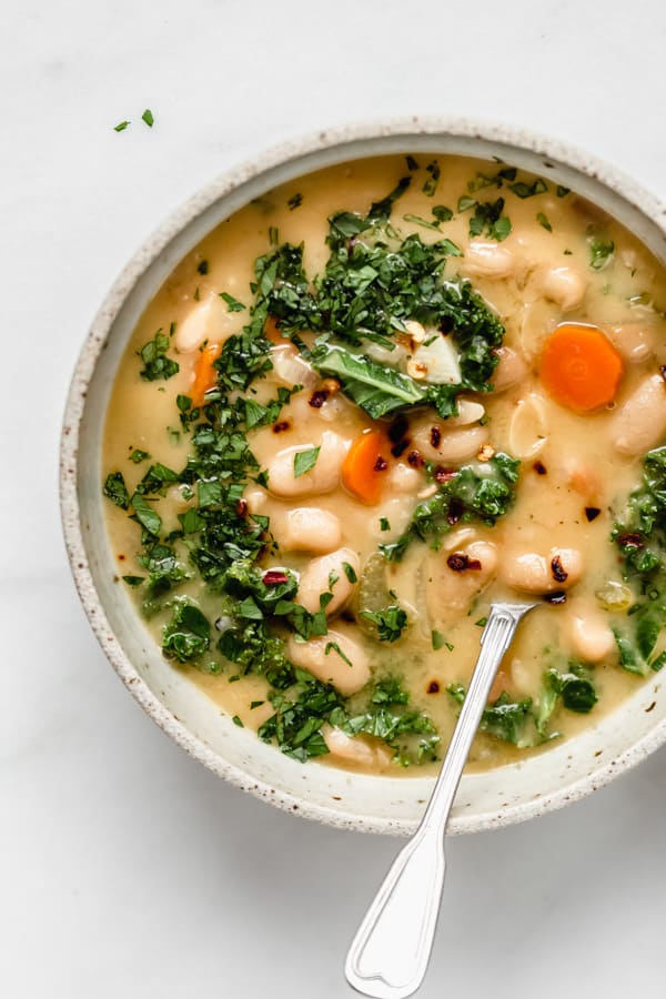 A bowl of tuscan white bean soup with a spoon in it