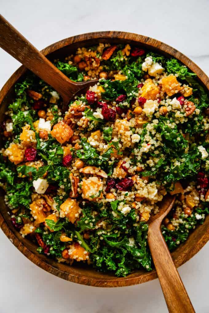 butternut squash and kale salad in a wooden bowl with wood salad spoons