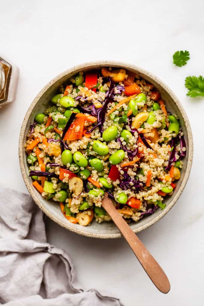 A bowl of edamame salad with a wood spoon in it