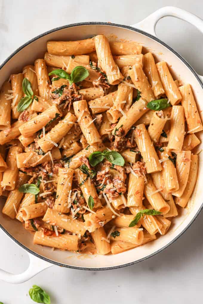 a pot of rigatoni in sundried tomato sauce with basil